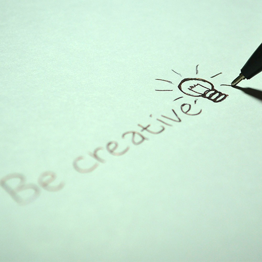 Doodle with the words be creative and a sketch of a lightbulb