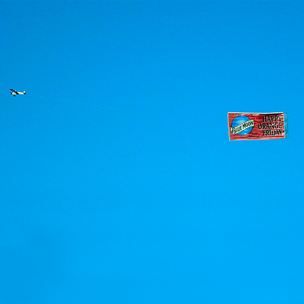 Airplane pulling an advertising flight banner across a blue sky